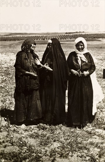 Palestinian bedouin women. Portrait of three Palestinian bedouin women standing in open countryside, two of whom are engaged in animated conversation. British Mandate of Palestine (Middle East), circa 1942., Middle East, Asia.