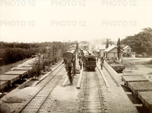 San Joseph railway station, Trinidad. Flatbed freight cars loaded with gravel sit beside passenger carriages at San Joseph railway station. San Joseph, Trinidad, circa 1912., Trinidad and Tobago, Trinidad and Tobago, Caribbean, North America .