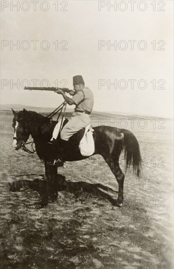 Arab officer of the Palestine Police Force. A mounted Arab officer of the Palestine Police Force takes aim with a rifle. British Mandate of Palestine (Middle East), circa 1938., Middle East, Asia.