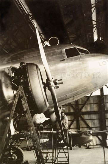 Inspecting a Royal Dutch Airlines aeroplane. Aviation mechanics inspect a KLM Royal Dutch Airlines aeroplane, the PH-ALV 'Valk', in a hangar in Lydda Airport. Lydda, British Mandate of Palestine (Lod, Israel), circa 1938. Lod, Central (Israel), Israel, Middle East, Asia.