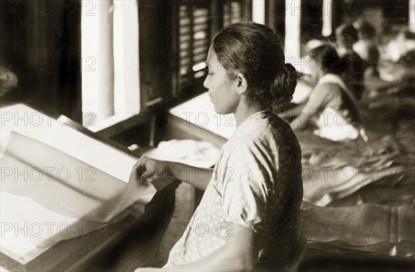 Sheets of latex in a rubber factory. A female factory worker examines sheets of latex at a rubber factory. Perak, British Malaya (Malaysia), September 1940., Perak, Malaysia, South East Asia, Asia.