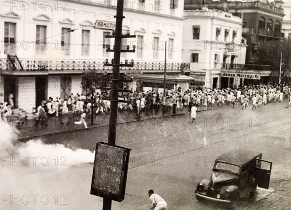 Tear gas disperses riots in Calcutta, 1946. Indian police use tear gas to disperse rioting crowds of Indian protesters on Old Court House Street. The photographer refers to the event as a "Communist riot", but it could be any one of a number of uprisings that plagued Calcutta in 1946. Two occasions that seem to fit are an attempt by student demonstrators to enter Dalhousie Square on 11 February, or the August riots relating to Direct Action Day. Calcutta (Kolkata), India, 1946. Kolkata, West Bengal, India, Southern Asia, Asia.