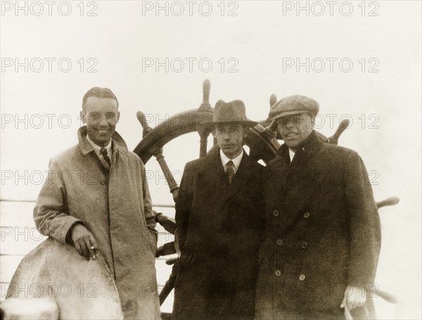 On voyage to India. Three British men on a sea voyage to India pose on deck beside the ship's wheel. Indian Ocean, September 1931., Indian Ocean, Africa.