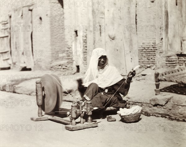 Silk spinner, India. An Indian woman sits by the roadside spinning silk using a 'charkha' or spinning wheel. United Provinces (Uttar Pradesh), India, January 1903., Uttar Pradesh, India, Southern Asia, Asia.