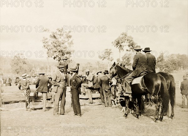 Men at an Australian sheep station. A large group of men, two on horseback, crowd around a wooden enclosure at a sheep station. Australia, May 1902. Australia, Australia, Oceania.