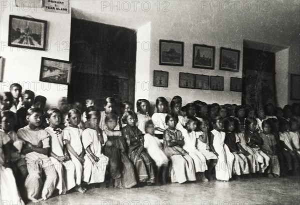 Chikmagalur Mission School. Primary school children at Chikmagalur Mission School sit in two long rows at the back of a classroom, listening attentively to an unseen teacher during a lesson. Chikmagalur, Mysore State (Chikkamagaluru, Karnataka), India, circa 1937., Karnataka, India, Southern Asia, Asia.