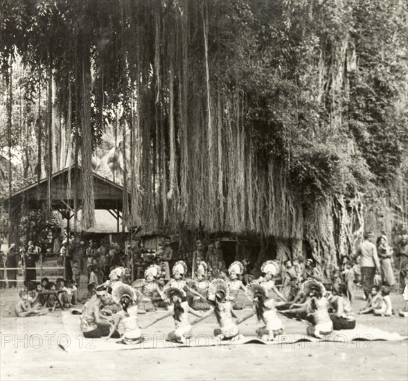 A traditional Balinese dance. Young Balinese men and women sit in a circle as they perform a traditional dance. They wear elaborate costumes, the men adorned with head bands and the women with fanned headdresses. Bali, Indonesia, July 1940., Lesser Sunda Islands (including Bali), Indonesia, South East Asia, Asia.