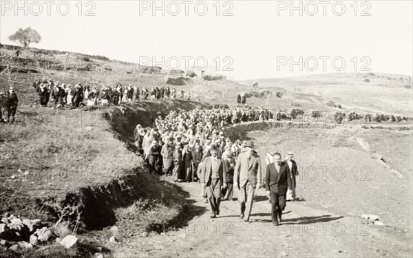 William Ryder McGeagh with Arab villagers. William Ryder McGeagh (centre), District Commissioner in Jerusalem, is followed by a procession of Arab men whilst visiting a rural Arab village. British Mandate of Palestine (Israel), circa 1940., Israel, Middle East, Asia.