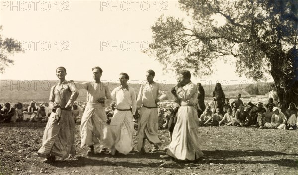 Dabke' dance at a Palestinian wedding. A group of men dressed in 'thobs' (ankle-length garments with long sleeves) perform a traditional 'dabke' folk dance at a Palestinian wedding. Salfit, British Mandate of Palestine (West Bank, Middle East), 17 September 1941. Salfit, West Bank, West Bank (Palestine), Middle East, Asia.