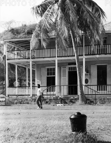 Nelson's House' in Antigua. A two-storey colonial building at Nelson's Dockyard, featuring wide verandas on its upper and lower floors. An original caption identifies it as Vice Admiral Horatio Nelson's house, and comments: 'It was from here that Nelson set out to defeat the French fleet'. English Harbour, Antigua, 1965. English Harbour, St Paul (Antigua and Barbuda), Antigua and Barbuda, Caribbean, North America .