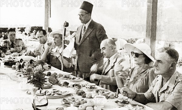 Farewell party for Sir Harold MacMichael. A government official identified as 'Rushdi' makes a speech at the farewell lunch of Sir Harold MacMichael (third from right), High Commissioner of the British Mandate of Palestine. MacMichael had survived an assassination attempt only four days prior to this photograph, and subsequently left Palestine on 31 August. Probably Jerusalem, British Mandate of Palestine (Israel), 12 August 1944. Jerusalem, Jerusalem, Israel, Middle East, Asia.