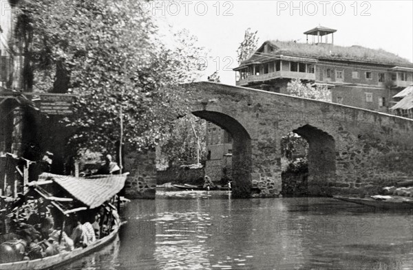 Canal bridge in Srinagar. A hump-backed stone bridge spans a Srinagar canal. Srinagar, Jammu and Kashmir, India, 1934. Srinagar, Jammu and Kashmir, India, Southern Asia, Asia.