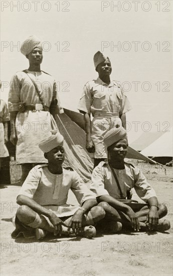 Arab soldiers with 'pagaris'. Portrait of four Arab soldiers at a military camp, wearing military uniforms and 'pagaris' (turbans). Their exact regiment is unknown, but related information suggests they belong to either the Somaliland Scouts, the Sudan Defence Force or, perhaps most likely, the Aden Protectorate Levies. Possibly Aden, Yemen, circa 1957. Aden, Adan, Yemen, Middle East, Asia.