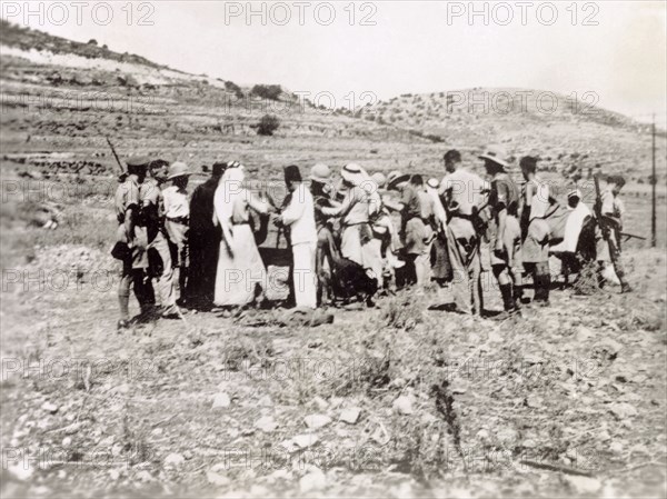 Searching a group of Arab villagers. British soldiers search a group of Palestinian Arab villagers for evidence of rebel activity. During the period of the Great Uprising (1936-39), an additional 20,000 British troops were deployed to Palestine in an attempt to clamp down on Arab dissidence. British Mandate of Palestine (Middle East), circa 1938., Middle East, Asia.