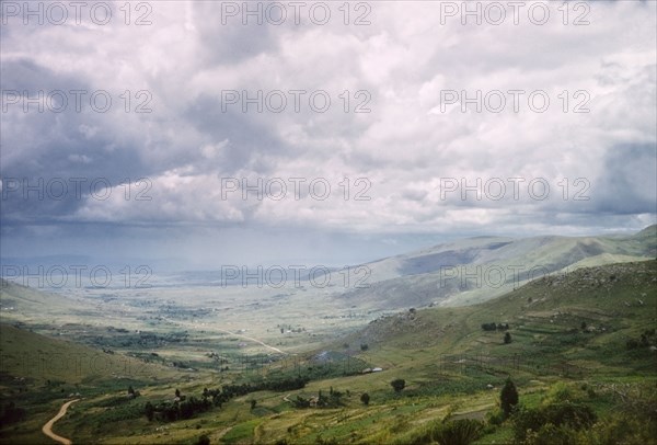 A view across Ankole. Rolling clouds hang over an extensive valley in Ankole. Terraced shambas can be seen on a hillside in the foreground. West Uganda, 1962., West (Uganda), Uganda, Eastern Africa, Africa.