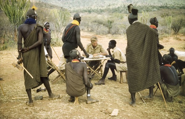 Paying the porters after safari. District Forest Officer James Lang Brown (centre) pays several Suk porters after a survey safari to the Karasuk hills. To his left sits Odong, a Ugandan Forest Guard. Kenya, 1959., East (Uganda), Uganda, Eastern Africa, Africa.