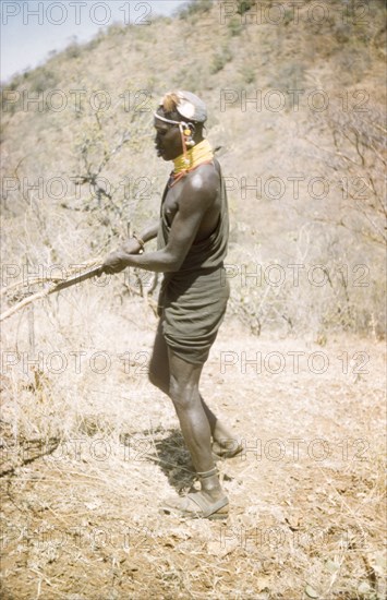 Lotuke clears the bush'. A Suk porter called Lotuke clears thorn scrub for a British forestry team surveying for new forest reserves sites in the Karasuk hills on the Kenya-Uganda border. Kenya, January 1959., East (Uganda), Uganda, Eastern Africa, Africa.