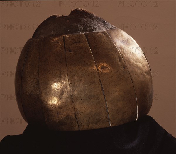 Brass helmet comprised of hammered plates and rondels fixed to a core of human hair and interwoven with twine