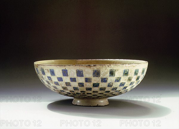 A pottery bowl with a blue and white chequer pattern on the outside