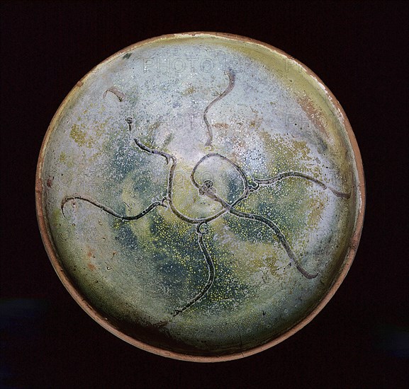 A redware pottery bowl with an abstract design scratched through the white slip before glazing