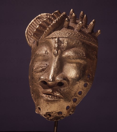 A gold pendant in the form of a stylized head