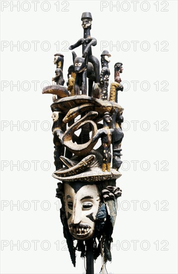 White faced Igbo mask with two tiered superstructure of polychromed figures, including a horse and rider and pythons