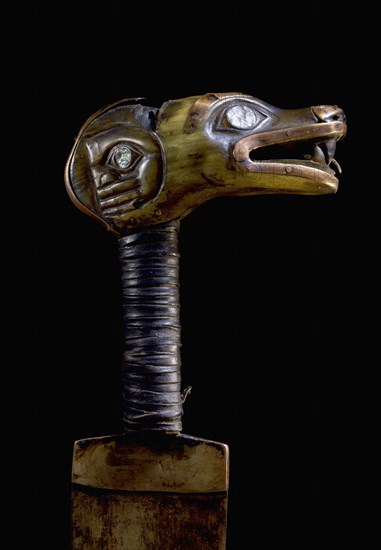 The handle of an iron bladed knife carved with a representation of the wolf totem