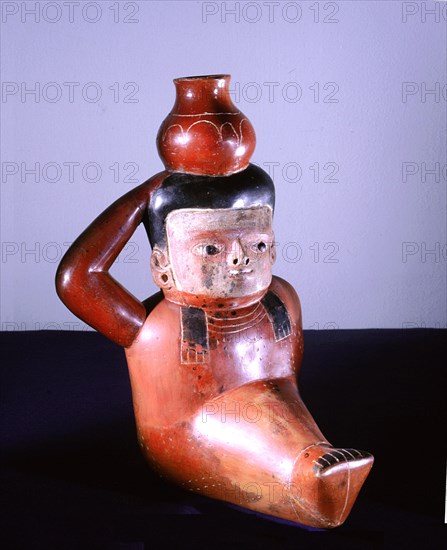 Polychrome jug in the form of a seated figure carrying a pot