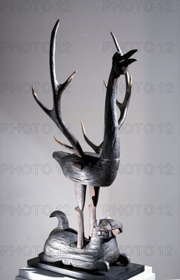 Sculpture of a phoenix with spread wings in the form of deer antlers, resting on a reclining tiger