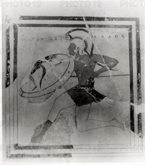 A terracotta slab painted with a running hoplite carrying a spear and shield