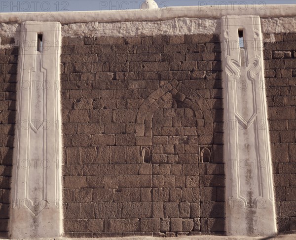 Incised plasterwork pilasters set into an old stone wall