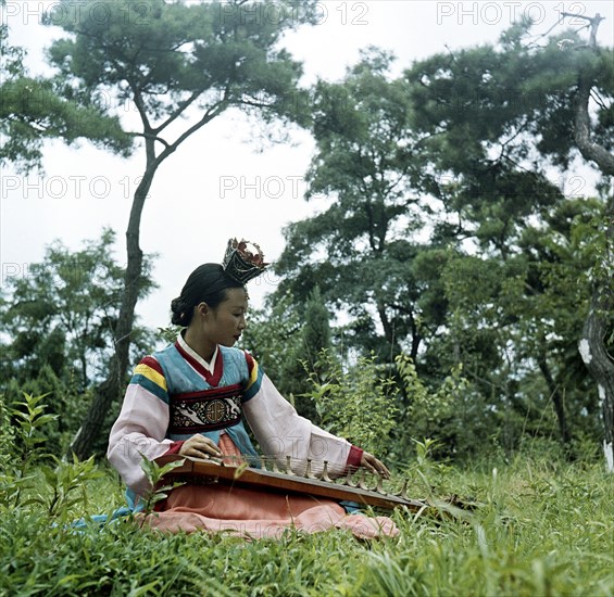 Korean lady in traditional dress playing musical instrument