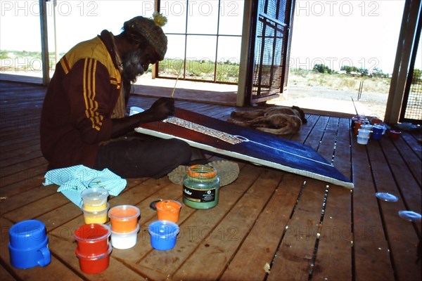 Desert artist Flakky Stevens painting on the verandah at the Warlayirti Culture Centre in the north-west desert region of Western Australia south of Halls Creek