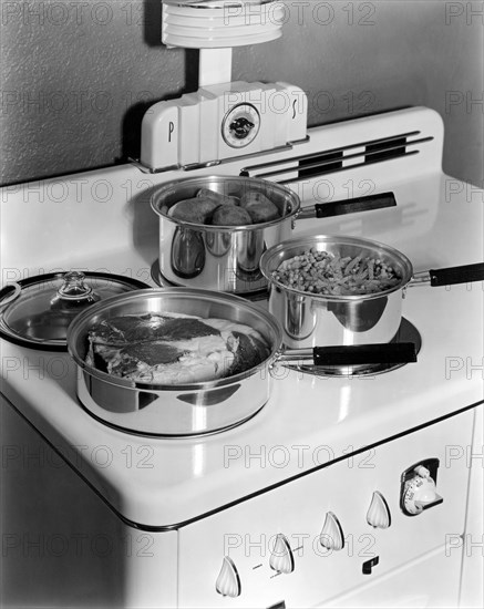 Beaver Dam, Wisconsin: c.1940.
A meal being cooked on the top of a Monarch Electric Stove, with the salt and pepper shakers built into the design.