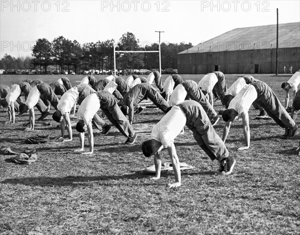 A group of men doing calisthetics on an athletic field