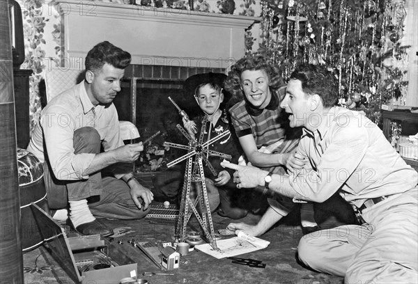 A small boy watches as his parents and friend play with his erec