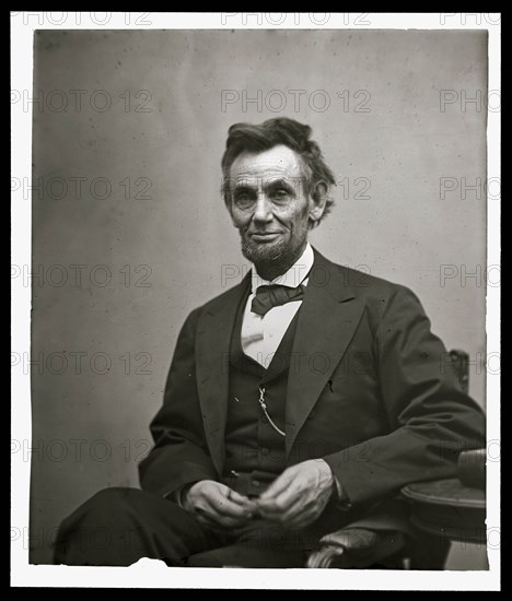 Abraham Lincoln, three-quarter length portrait, seated and holding his spectacles and a pencil 1865