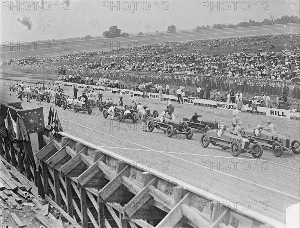 Auto racers at Speedway line up at starting line to begin the race. 1925