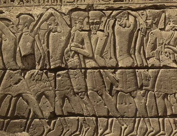 Bas-relief of several men, standing, left of the door of the Great Temple at Medinet-Abou 1880