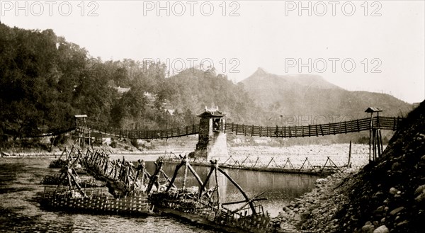 Chinese built suspension bridge, boats docked at pier in foreground, Szechwan Province, China