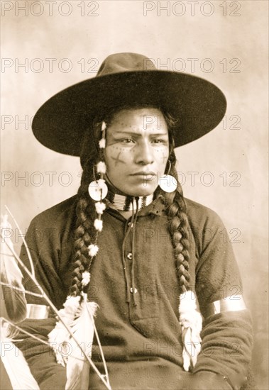 Portrait of Indian with decorated face, feather and bead ornaments,  1903