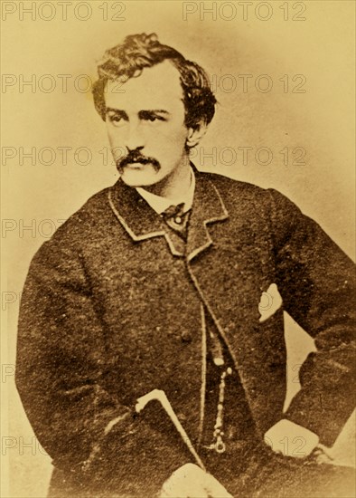 John Wilkes Booth, half-length portrait, facing left and holding a cane 1860