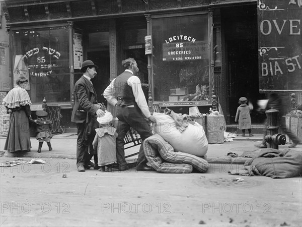 Outside of a Jewish Butcher Shop, Evictees look over their possessions