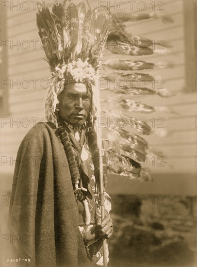 Piegan war-bonnet and coup-stick 1910