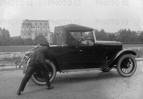 Suited man pushes his coupe from behind