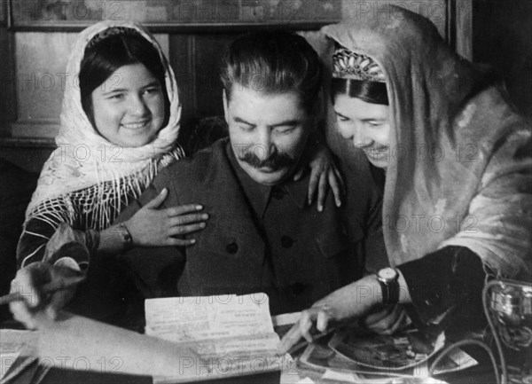 Joseph stalin with two young women from a collective farm in tadjikistan at a conference on cotton farming, january 1935.