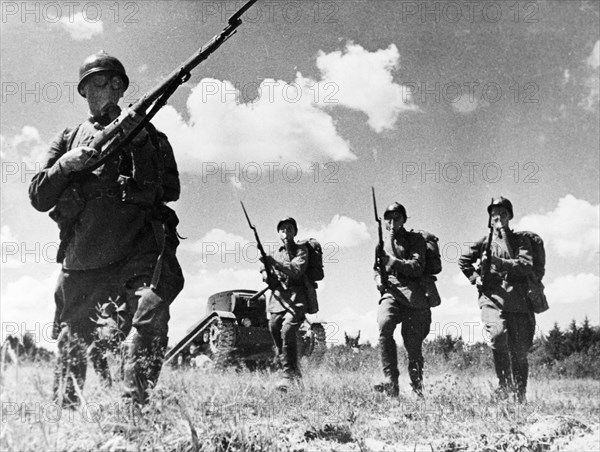 Soviet infantry in gas masks, supported by light tanks during training exercises, 1940.