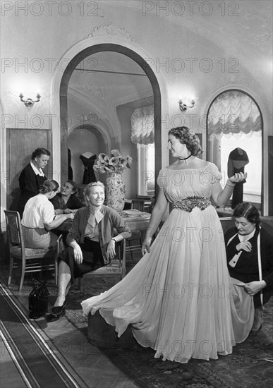 A woman trying on a dress at a tailoring shop in moscow, november 1955.