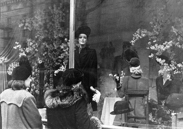 Two women looking at coats and hats on display in a window of the central department store in moscow, 1940s.