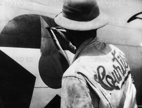 World war 2, lend-lease, a man painting out the american insignia with red paint for delivery of the plane to russia, iran.